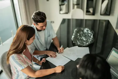 Mid adult couple signing documents at home